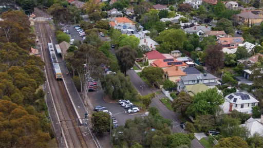Aerial showing train at platform surrounded by houses and trees