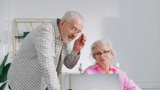 An older man and woman looking at a computer