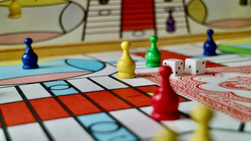 Colourful game pieces and a dice sit on a board game.