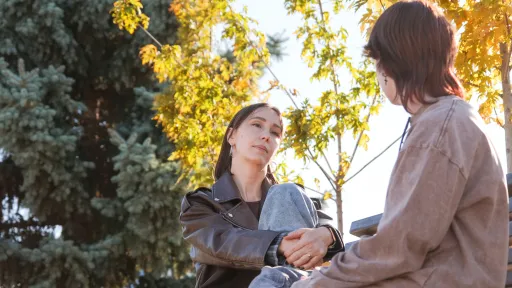 two young people sitting and talking outside.