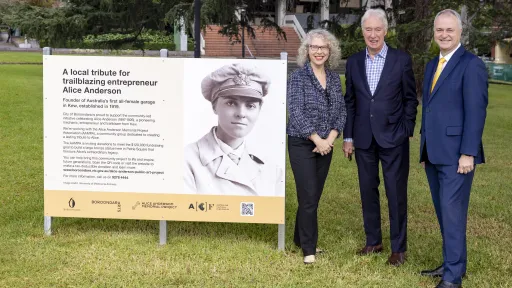 Commemorative plaque beside which 3 people in suits stand