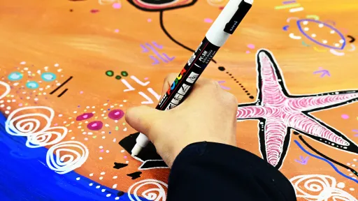 A person is drawing on a colorful indigenous image