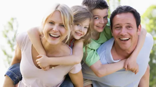 2 adults and 2 children smiling. The children are on the adults backs.