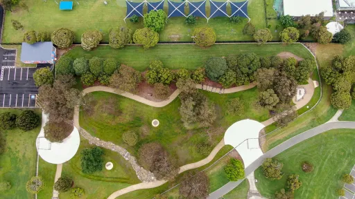 Arial view of Gordon Barnard Dog Park. A fenced area with trees, paths and difference surfaces.
