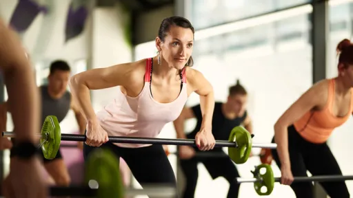 A group fitness session with people lifting barbells with small weights.
