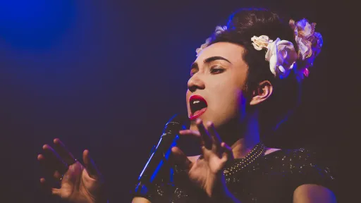 Performer with flowers in hair sings into microphone