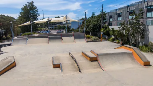 A large skate park with ramps, rails and different sized slopes for different skill levels.