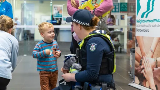 A child talks to a police officer kneeling towards them