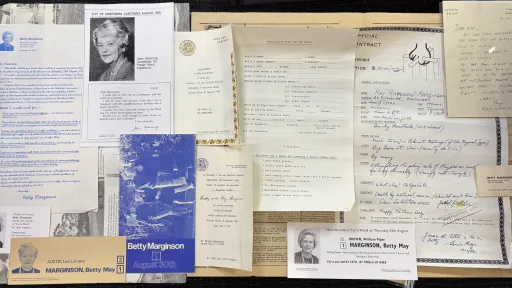 A variety of newspaper clippings and handwritten notes sit on a table