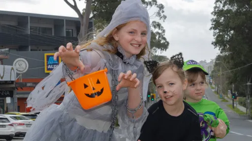 Three kids in Halloween outfits with a pumpkin bucket