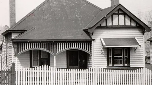 Black and white image of timber house with small timber fence out the front