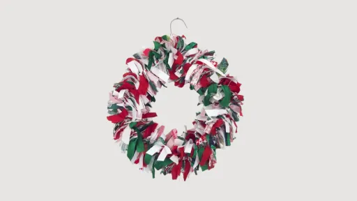 A Christmas wreath made from strips of green, red and white fabric.