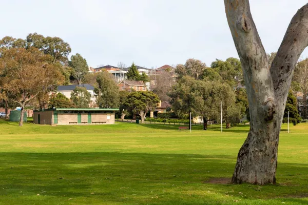 A view across a green sportsfield looking towards a brick building. 