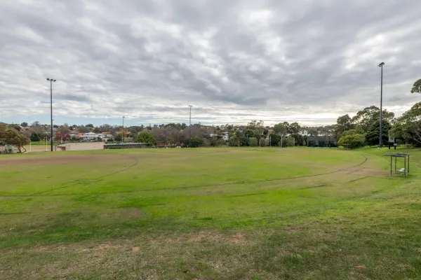 A circular sportsground. Sheltered seating can be seen to the right of the oval. 