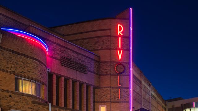 The Rivoli Theatre at night with its neon signs lit up