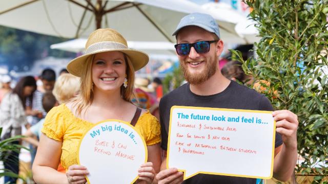 2 people outside looking at the camera holding signs with handwriting on them