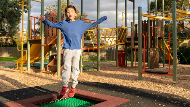 Child bounces on trampoline at playground