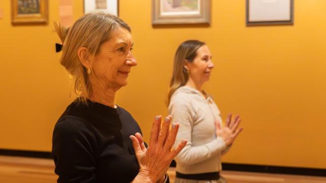 Two women doing yoga in an art gallery