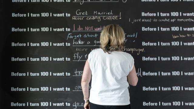 A woman with her back to us writes on a blackboard