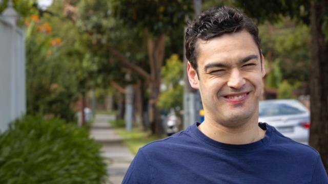 A smiling young man on a neighbourhood street