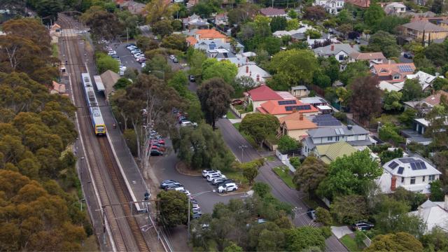 Aerial showing train at platform surrounded by houses and trees