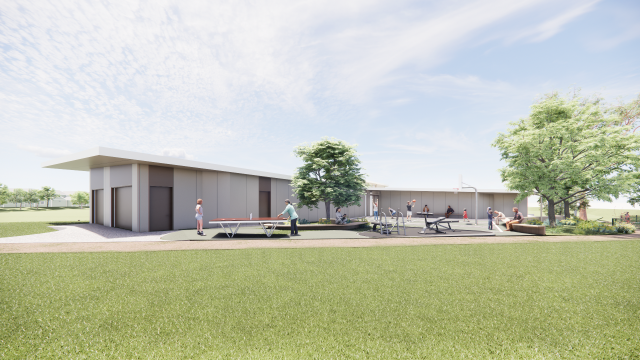 A long, single story building. Next to it is a half basketball court, exercise equipment and a table tennis table.