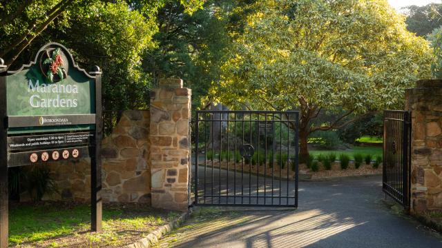 The iron gates are open to Maranoa Gardens on a sunny late afternoon