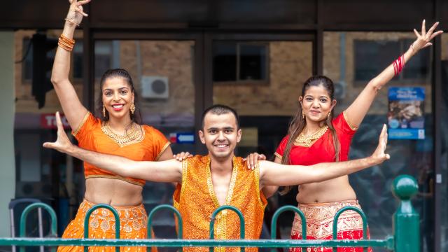 3 people dressed in orange hold their arms out