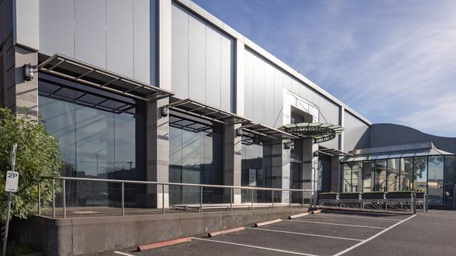 Grey metal-clad building in car park