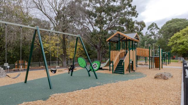 Three swings and a timber climbing unit at a playground