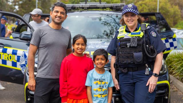 A family stand with a police officer in front of a police car.